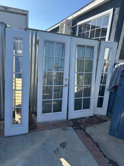 Durable white wooden waterproof French doors with two matching sidelights. This set has a 15-lite glass design on the main doors and a 5-lite design o