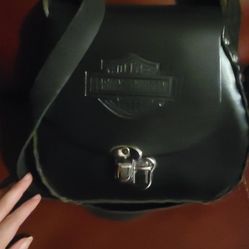 Harley-Davidson black leather crossbody or hip bag featuring an embossed Bar & Shield logo on the flap and a distinctive metal turn-lock closure. The 