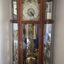 This is a Ridgeway curio grandfather clock with a polished brass-finished dial 