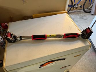 stainless steel horizontal pull-up bar features red foam padding, a safety locking mechanism, and adjustable ends designed for doorway installation.