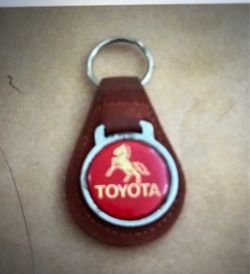 Vintage Toyota leather key ring featuring a red enamel badge with the iconic stallion logo.