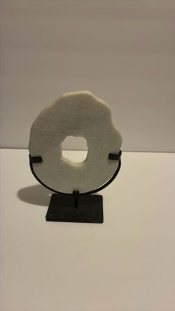 white marble crystal shaped sculpture rests in a custom black iron stand