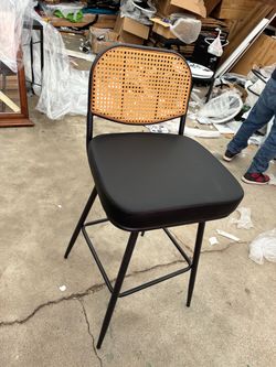 Two black leather bar stools rattan back