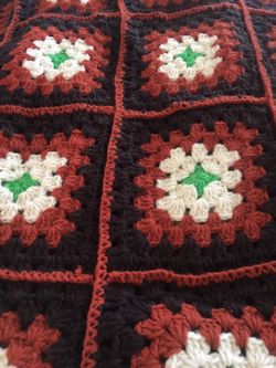 Patchwork hand crocheted quilt approximately 80x98. Colors are brown,rust,ivory and green.