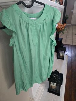 Light seafoam green blouse with delicate ruffle sleeves. Soft, breathable fabric for all-day comfort. Button-front keyhole and subtle pleat detail at 