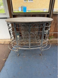 Elegant wrought iron wine/bar cabinet with decorative scrollwork, stone-look top, and built-in wine bottle storage