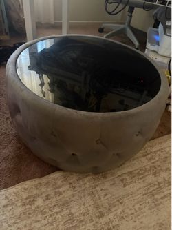 Round upholstered coffee table with glass top