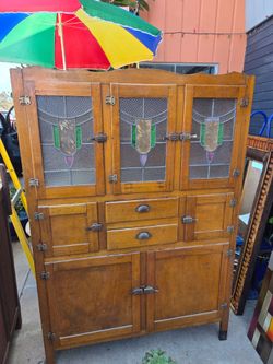 Antique wooden kitchen cabinet featuring upper leaded-glass doors—a traditional style from the early 20th century.