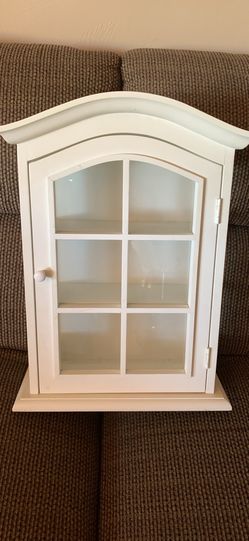White wooden curio cabinet with arch top, glass door.