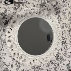 round wall mirror with a white, ornate