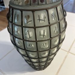 vintage mossy green caged glass vase with a wrought iron stand.  The glass is frosted and features a distinctive pattern of clear, square-shaped cutou