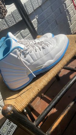 Nike Air Jordan 12 Retro "Melo" sneakers, featuring a primarily white leather upper with university blue accents along the mudguard and sole.