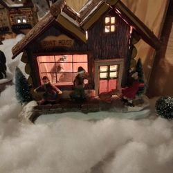 Lighted glass window house with interior and exterior figurines.  This one is the Boat House.