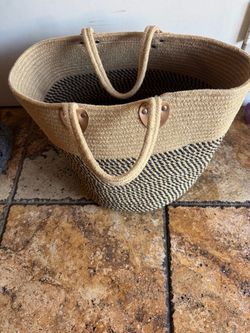 Spacious woven wicker storage basket in natural with black accents. Lightweight and durable for everyday use. Comfortable double handles for easy carr