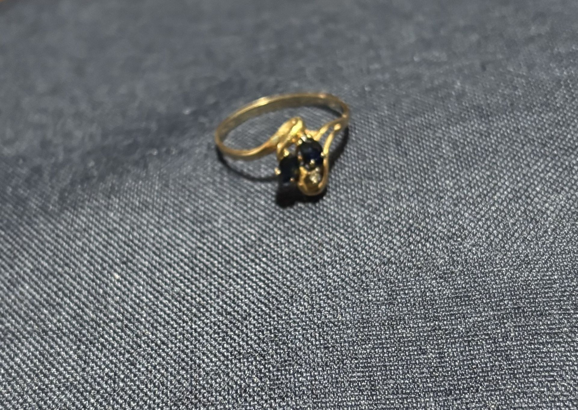 Elegant gold ring with blue sapphires and a diamond.