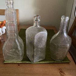 Three antique clear glass liquor bottles