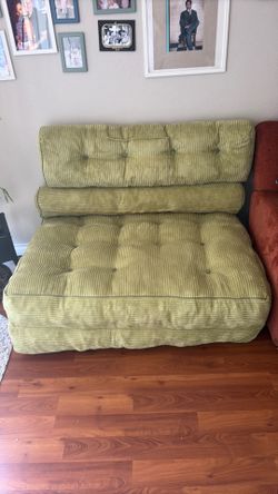Green cushion sofa with 2 long pillow and turns into a bed at night if you have stay over.