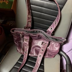 A slouchy satchel or tote style with distinctive grommeted shoulder straps and decorative buckles.