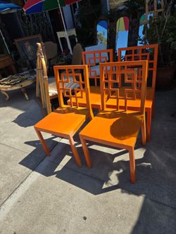 four West Elm Overlapping Squares-style wooden dining chairs with an orange finish