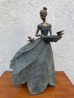 a Bronze decorative fairy garden statue and bird feeder, unique skirt by textured green leaves