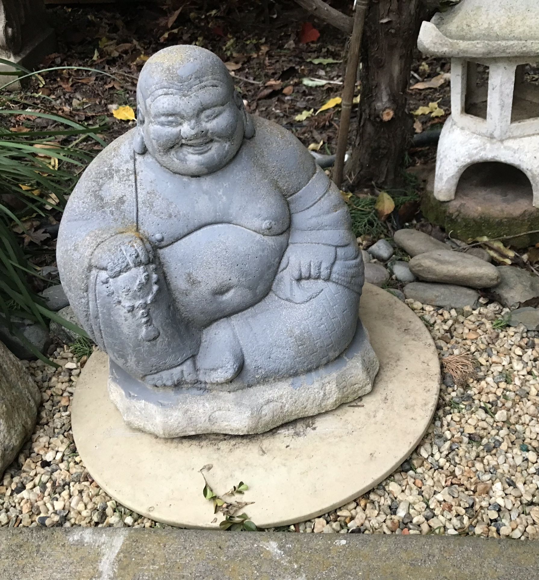 A small cement Asian Buddha garden statue