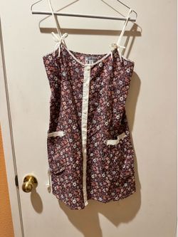 Sleeveless lightweight adjustable shoulder top. Cream button-front placket and pocket trim. All-over small floral pattern. Casual, easy-to-wear silhou