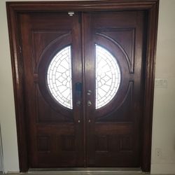 This is a beautiful double wooden entry door with a rich, dark wood finish. Each door features a cir