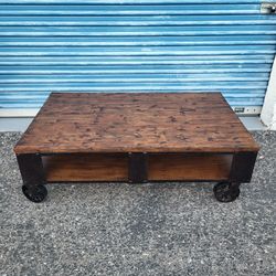 Mountainier coffee table. Industrial style with iron wheels. Measures approx: 52" wide 