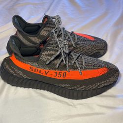 MAKE AN OFFER! Mens size 12 Adidas Yeezy Boost 350 V2 Carbon Beluga sneakers, featuring a dark grey Primeknit upper and a vibrant orange side stripe