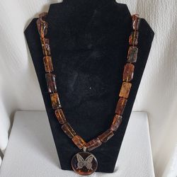 Amber women's necklace has a medallion with a silver butterfly