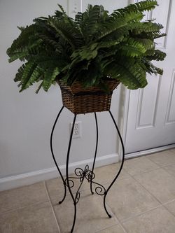 Beautiful Silk fern plant in a wicker basket and decorative metal stand