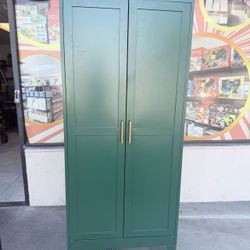A green metal storage wardrobe with 2 adjustable shelves, featuring a stacking area and a hanging area. It can be used as a tool cabinet or wardrobe i