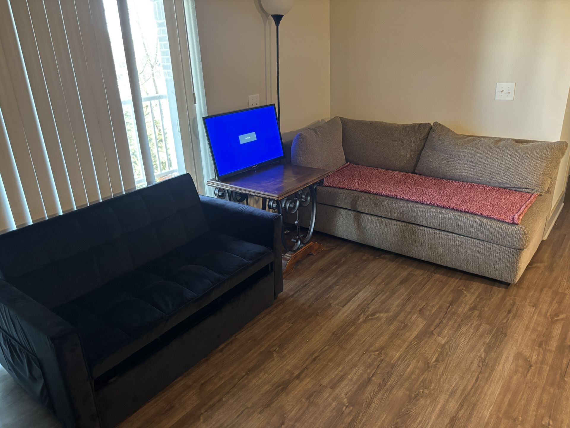 A futon couch with a pull-out bed, a small loveseat, a small TV, and a wooden table. ALL IN ONE :)