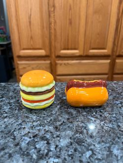 Ceramic Hot Dog on Bun and Cheeseburger Ceramic pair of Salt and Pepper Shakers.  Size approximately tallest 2 inches tall and hot dog 2 1/2 inches lo