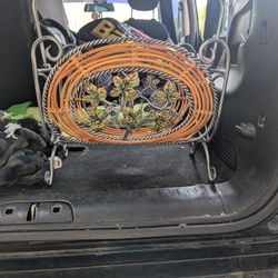 vintage metal and orange rattan magazine rack with a decorative leaf and vine motif. 