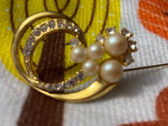 vintage gold-tone swirl brooch accented with clear rhinestones and a cluster of faux pearls.