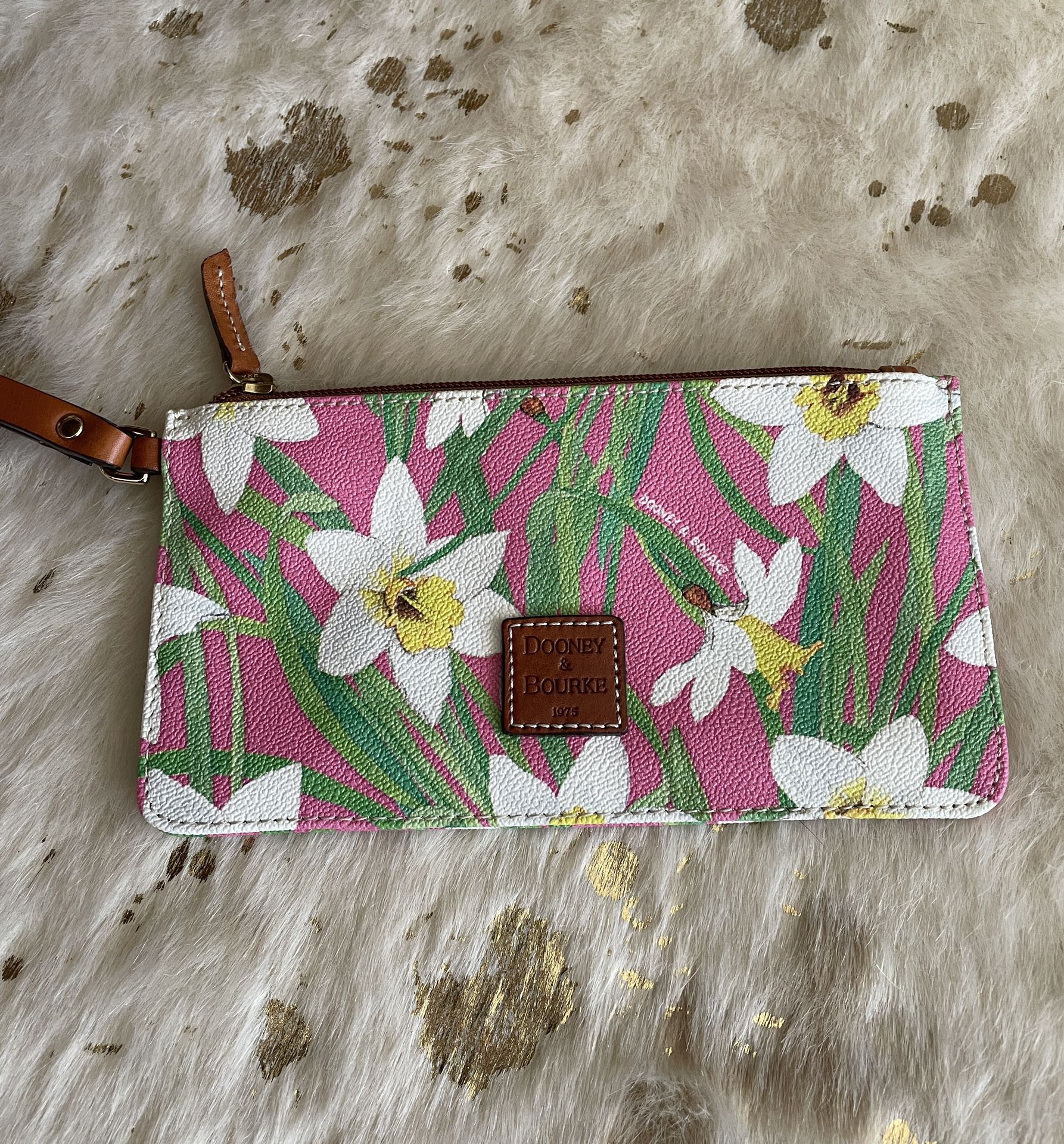 Perfect for Spring!  Dooney & Bourke coated canvas wristlet in pink and white daffodil print with leather strap and logo square.  Excelled pre-owned c