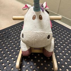 Plushy unicorn rocking toy with wooden handles.