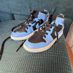 These are Nike Air Jordan 1 Mid sneakers in the "University Blue Black" colorway, typically styled for kids. 