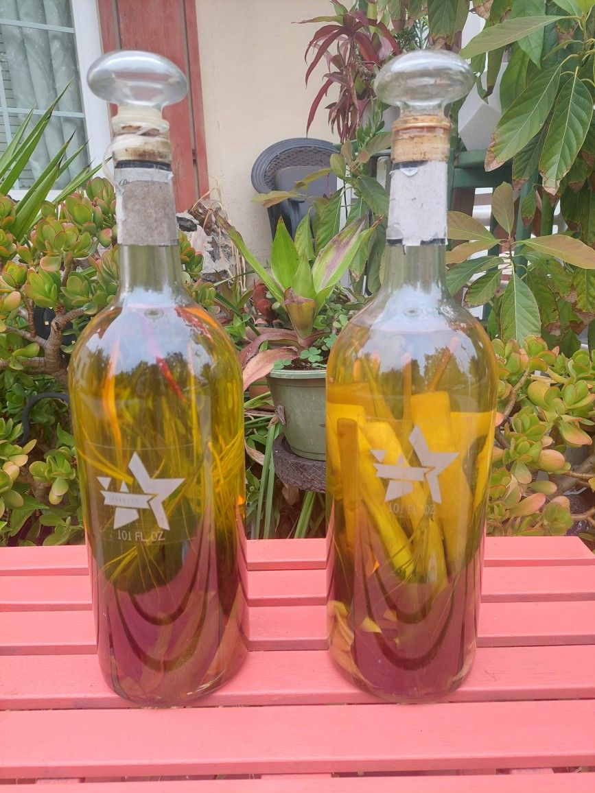 PAIR OF ORNAMENTAL BOTTLES FILLED WITH VEGGIES INFUSED IN OLIVE OIL .