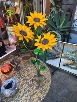 Handcrafted metal garden sunflowers with green stems and a perched hummingbird.