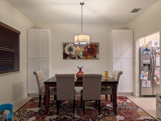 Dark Wood Dining Table with 6 Chairs, 1 chandelier, 1 rug, and 1 wall art