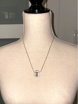 The necklace features a silver floating circle pendant with a central cylinder encrusted with crystals.