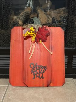 Handcrafted wooden pumpkin-shaped fall decoration finished in a warm rustic orange-red color. Decorated with artificial autumn leaves, berries, burlap