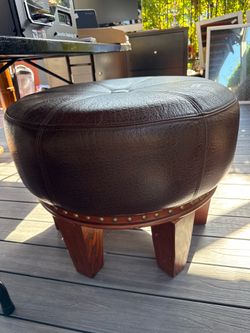 Brown leather ottoman, round with wooden legs