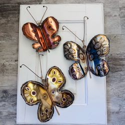 set of three vintage metal  butterfly wall hangings  each butterfly has a different metal coloring one is copper  7” tall including antennas x 5” wide