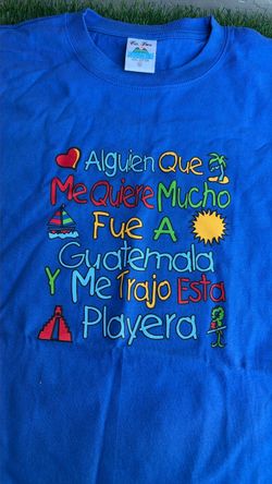 playera azul de recuerdo con el texto bordado "Alguien que me quiere mucho fue a Guatemala y me trajo esta playera".