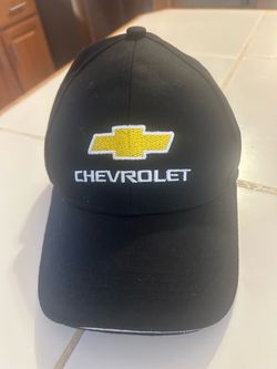 black cotton baseball hat featuring an embroidered gold Chevrolet bowtie logo and white "CHEVROLET" text on the front panel.