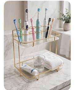 Double-tier gold metal and glass tabletop organizer for toothbrushes and toothpaste—featuring a "light luxury" style.