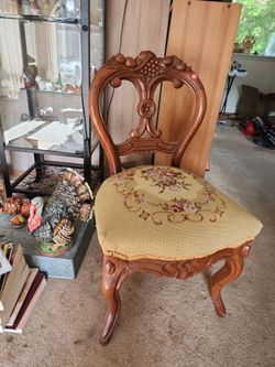 walnut balloon-back Victorian parlor chair featuring a carved wood frame and a floral needlepoint seat.